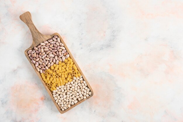 Top view of pile of Bean, pasta and chickpea on wooden tray. 