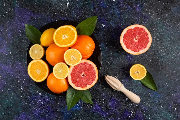 Top view of pile of fruits on black plate.