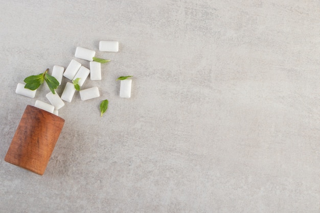 Top view of pile of gums with mint leaves on grey background. 