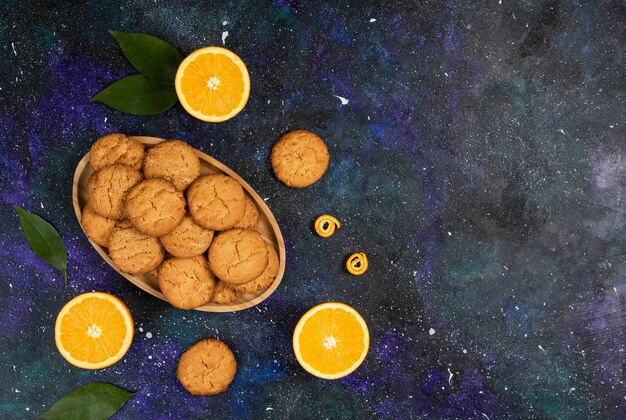 Top view. Pile of homemade fresh cookies and cookie with orange over space surface.