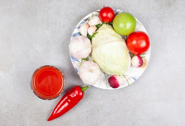 Top view of pile of organic vegetables on plate and sauce over grey surface.