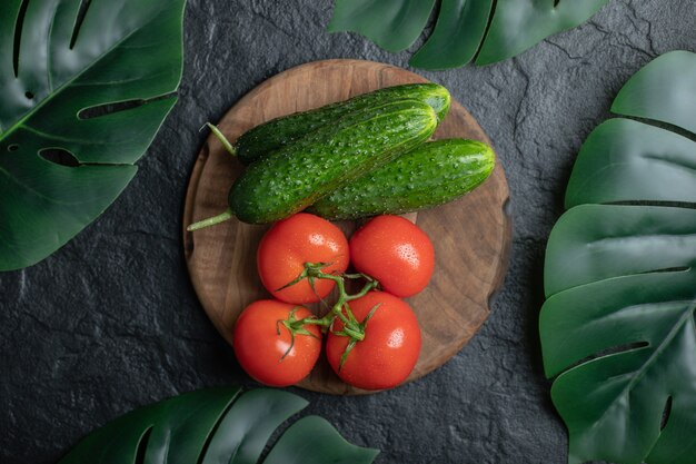 Top view of pile of vegetables on wooden board. Cucumber and tomatoes . 