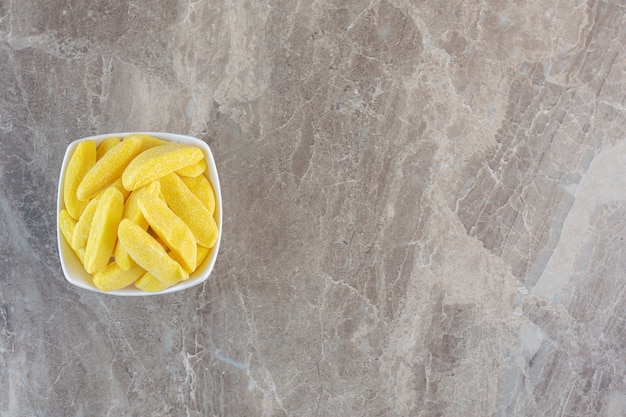 Foto gratuita vista dall'alto del mucchio di caramelle gialle in una ciotola bianca.