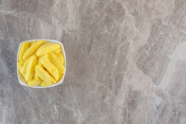 Top view of pile of yellow candy in white bowl.