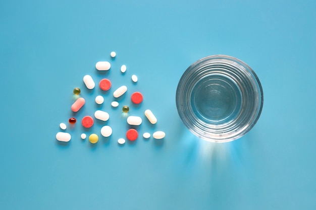 Free photo top view of pills in triangle shape with glass of water