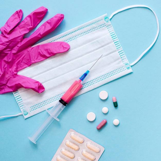 Top view of pills with medical mask and syringe