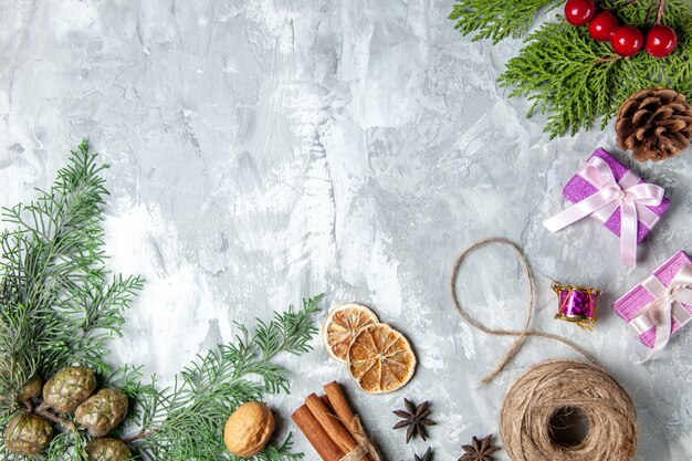 Top view pine tree branches cinnamon sticks straw thread anises on grey background free space