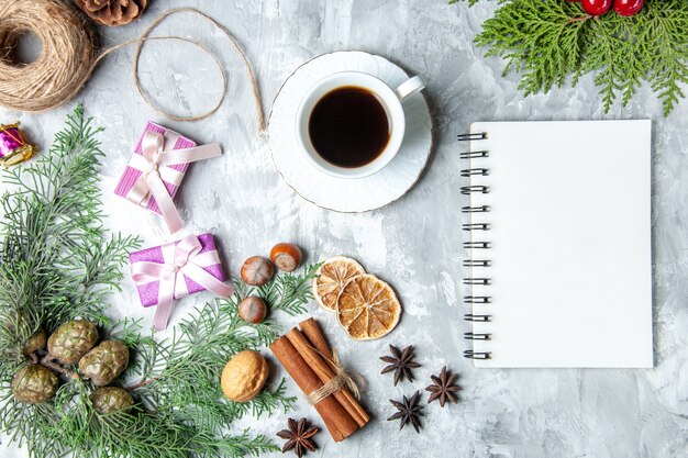 Top view pine tree branches cinnamon sticks straw thread notebook cup of tea on grey background