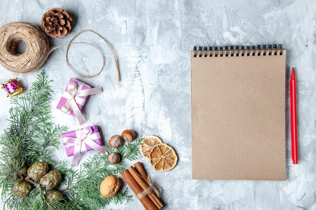 Top view pine tree branches cinnamon sticks straw thread notebook red pencil on grey background