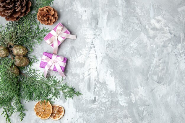 Top view pine tree branches lemon slices pinecones small gifts on grey surface