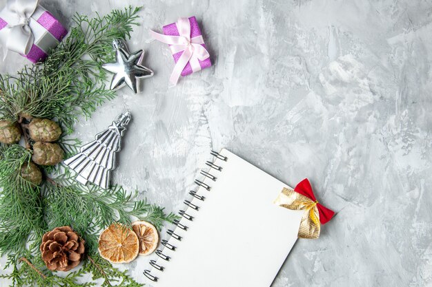 Top view pine tree branches notebook pinecones small gifts dried lemon slices on grey surface