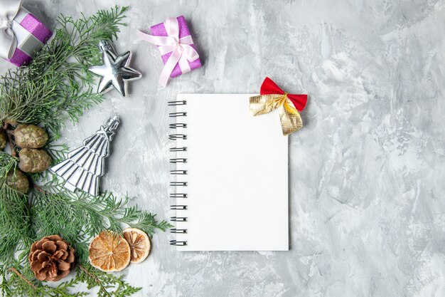 Top view pine tree branches notebook pinecones small gifts on grey surface