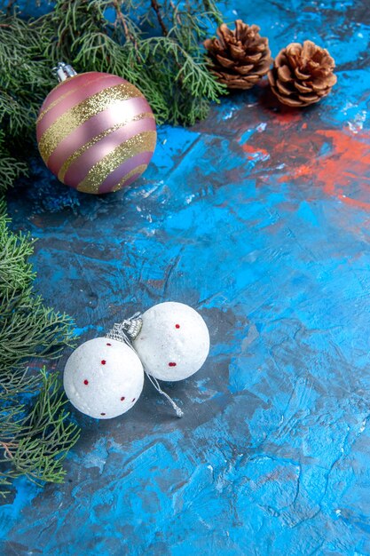 Top view pine tree branches pinecones xmas tree balls on blue-red surface