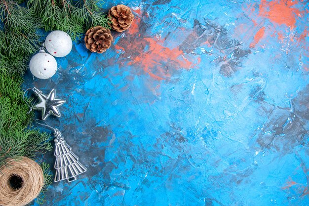 Top view pine tree branches pinecones xmas tree balls straw thread on blue-red background