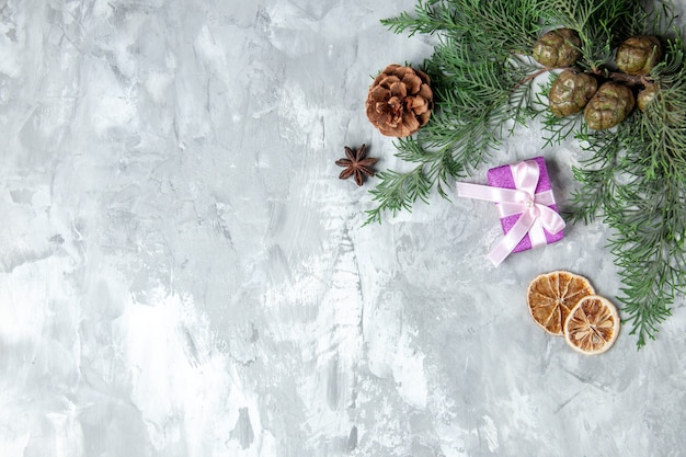 Top view pine tree branches small gift dried lemon slices on grey background