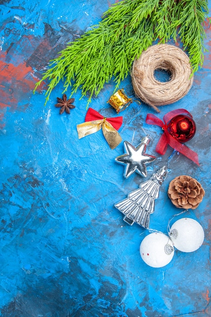 Free photo top view pine tree branches straw thread xmas tree toys anise seed on blue-red background