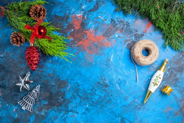 Top view pine tree branches with pinecones hanging ornaments straw thread on blue-red surface