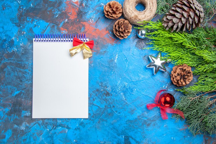मुफ़्त फोटो top view pine tree branches with pinecones straw thread xmas toys a notebook on blue-red background free space