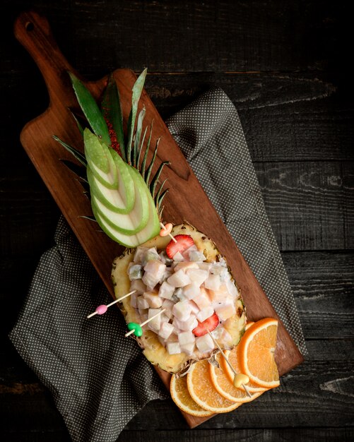 Top view of pineapple bowl salad with fruit cubes in cream