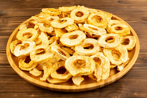 a top view pineapple dried rings inside plate dried fruits sour tasty unique taste on the brown wooden desk fruits exotic dry
