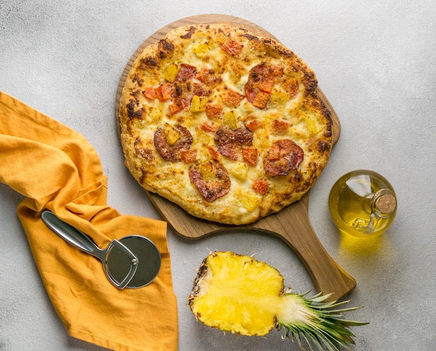 Free photo top view of pineapple pizza with oil and cutter