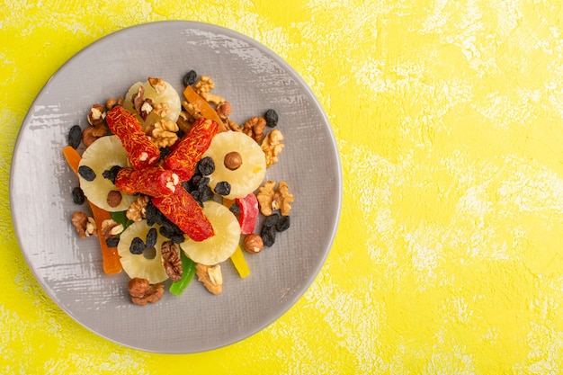 Free photo top view of pineapple rings along with dried fruits and nougat inside plate