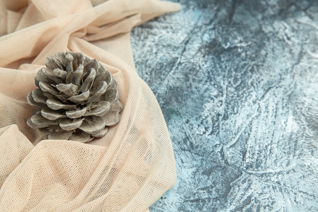 Top view pinecone on beige shawl on dark surface free space