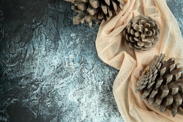 Top view pinecones on beige shawl on dark surface copy space