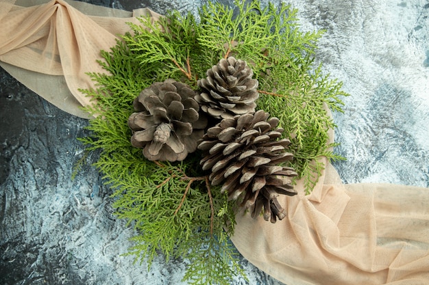 회색 표면에 베이지 색 목도리에 상위 뷰 pinecones 소나무 가지