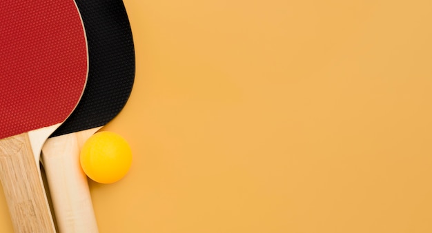 Top view of ping pong paddles with ball and copy space