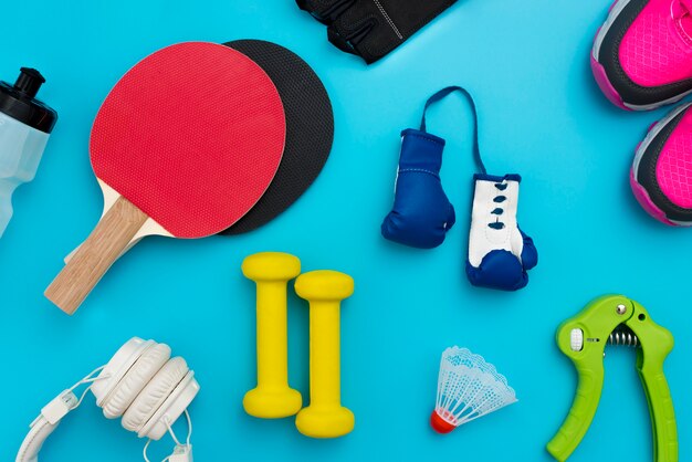 Top view of ping pong paddles with boxing gloves and sport essentials