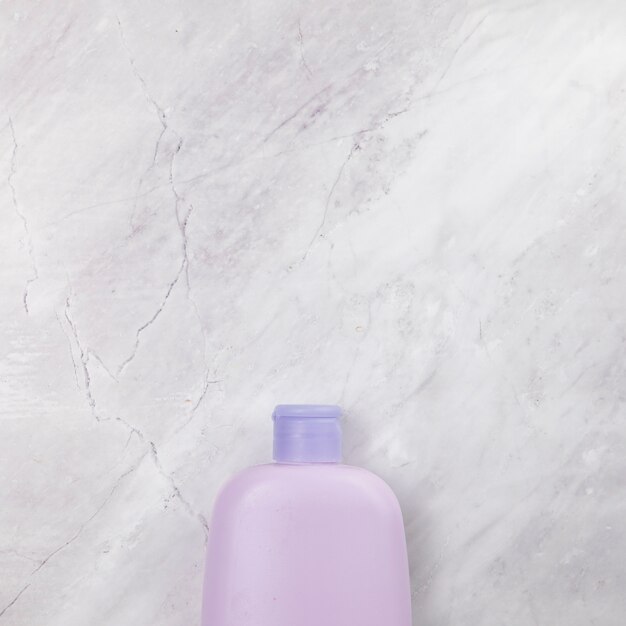 Top view of pink bottle on marble background