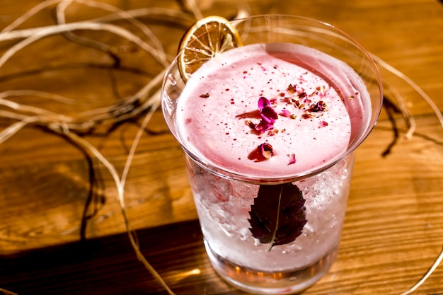 Top view of pink cocktail garnished with dried rose petals