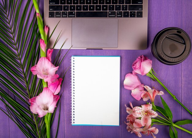 Вид сверху розового цвета гладиолуса и розы с цветами альстромерии, расположенными вокруг ноутбука для рисования и бумажного стаканчика кофе на фиолетовом фоне