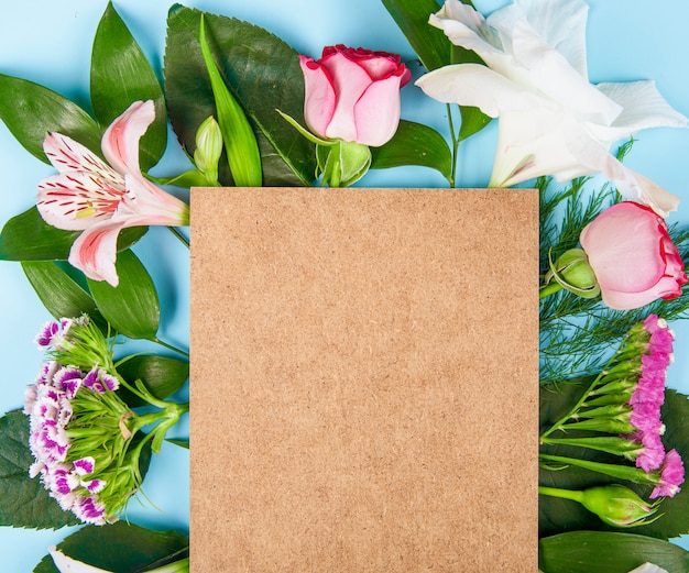 Top view of pink color roses and alstroemeria flowers with turkish carnation with a brown sheet of paper on blue background