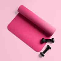 Free photo top view of a pink fitness mat and two black dumbbells isolated on a pink surface