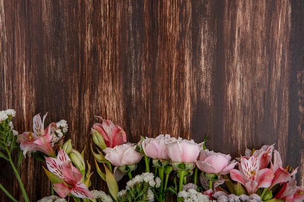 Top view of pink lilies with pink roses on a wooden surface