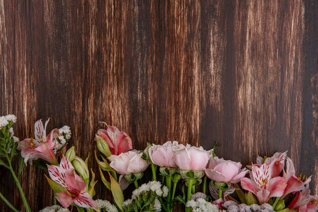 Top view of pink lilies with pink roses on a wooden surface