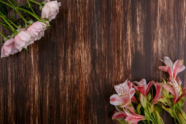 Top view of pink lilies with pink roses on a wooden surface