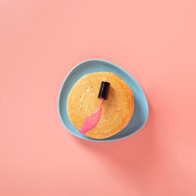 Top view of pink nail polish on pancakes with plain background