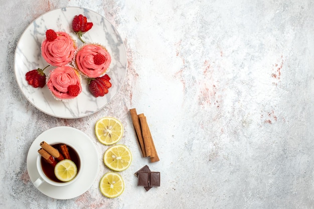 Top view of pink strawberry cakes with fresh red strawberries on a white surface