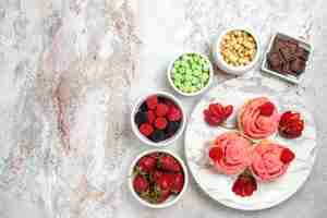 Free photo top view of pink strawberry cakes with nuts and candies on a white surface