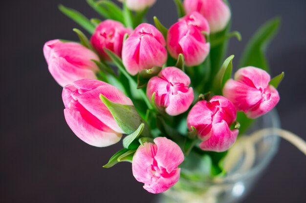 Top view of pink tulips with green leaves in a vase