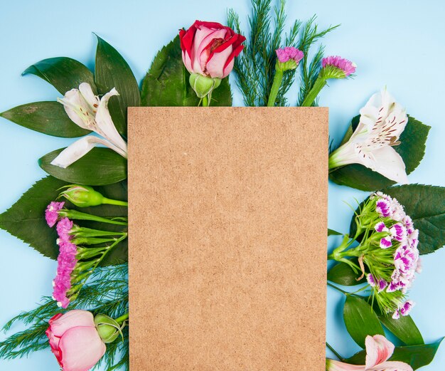 파란색 배경에 종이의 갈색 시트와 터키 카네이션과 statice 분홍색과 흰색 색 장미와 alstroemeria 꽃의 상위 뷰
