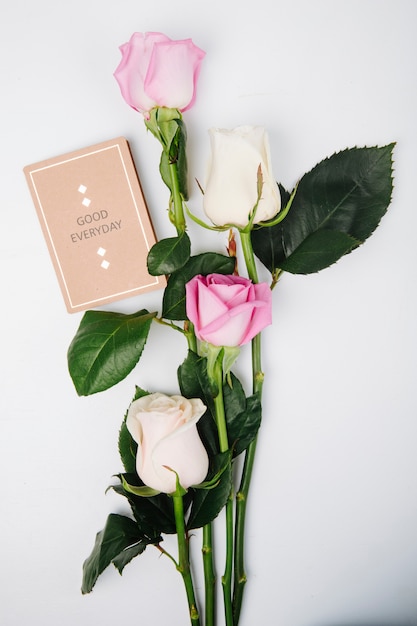 Free photo top view of pink and white color roses with small postcard isolated on white background