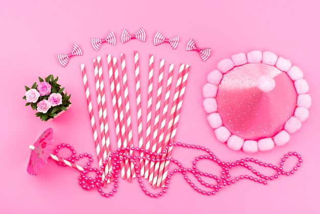 A top view pink-white stick candies along with birthday cap cute pink, bows on pink, birthday color