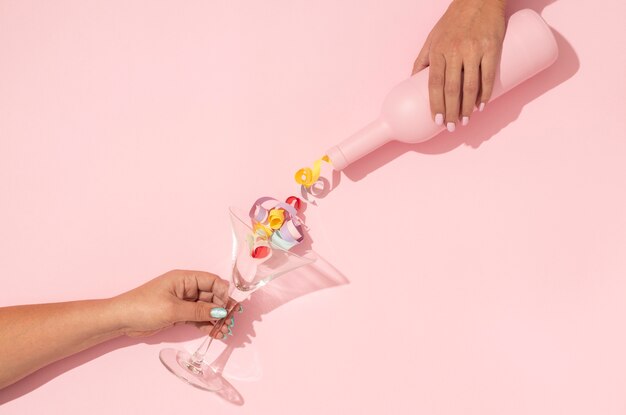 Top view of pink wine bottle pouring confetti in glass for valentines day