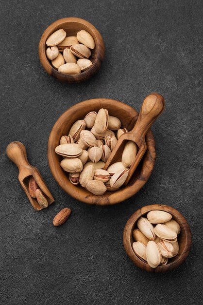 Top view pistachio nuts in bowls with wooden spoons