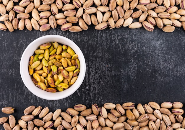 Free photo top view pistachios in a bowl on gray texture  with copy space horizontal