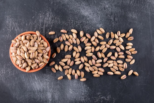 Top view pistachios in a bowl on gray texture